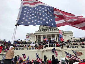 a group of people standing in front of a crowd: Rioters stand on the US Capitol building to protest the official election of President-elect Joe Biden on Jan. 6, 2021 on Washington DC.