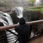 a man standing next to a waterfall: Great Falls during an April rain