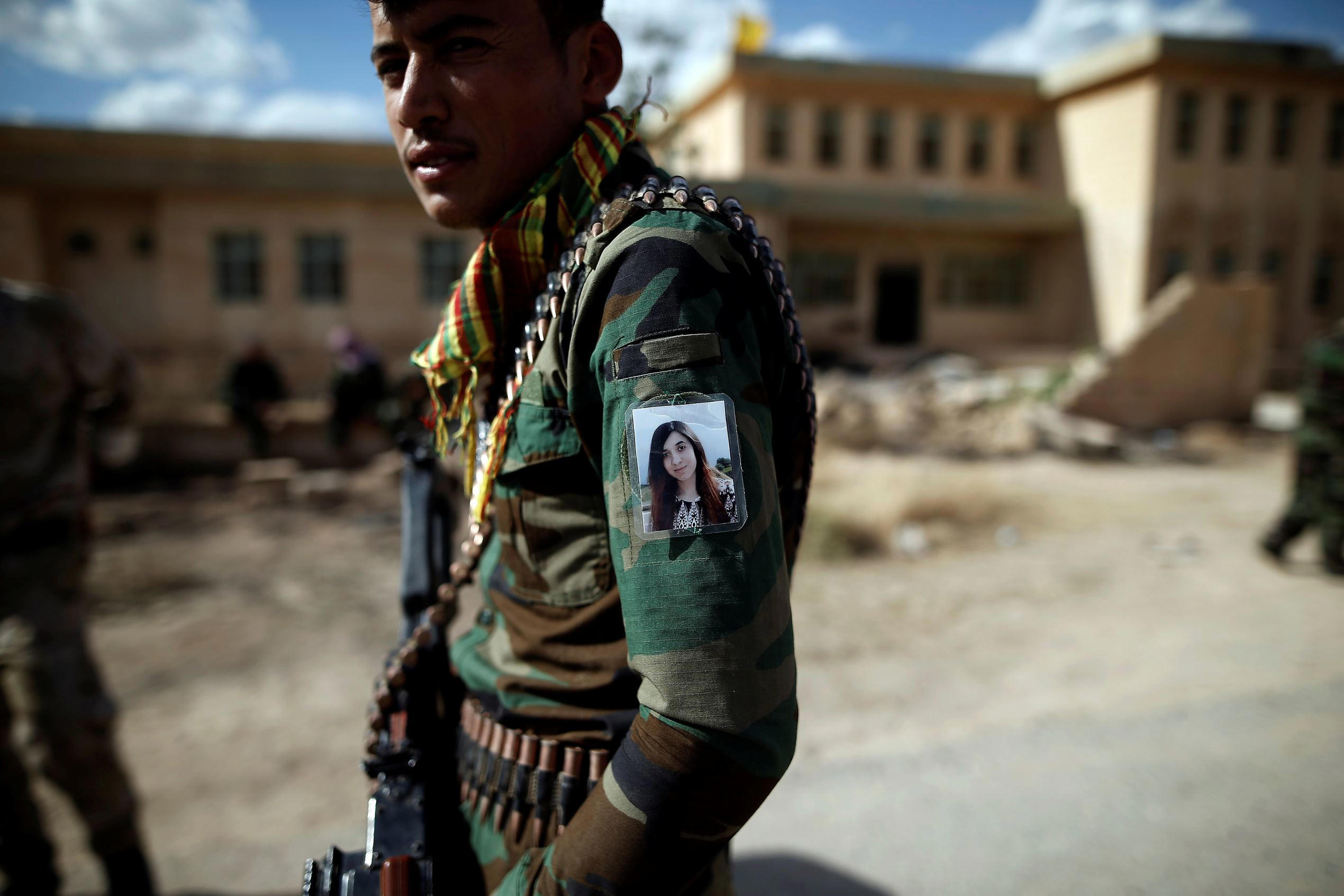 Slide 1 of 105: Yazidi Popular Mobilisation Forces (PMF) fighter Hussein Eisso, 21, hangs a photo of Yazidi survivor and United Nations Goodwill Ambassador for the Dignity of Survivors of Human trafficking Nadia Murad on his arm in Kojo, Iraq June 1, 2017. REUTERS/Alkis Konstantinidis TPX IMAGES OF THE DAY