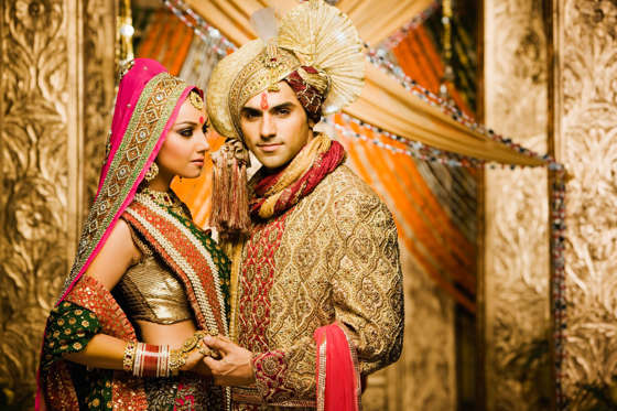 Slide 1 de 17: Portrait of bride and groom wearing traditional Indian clothing.