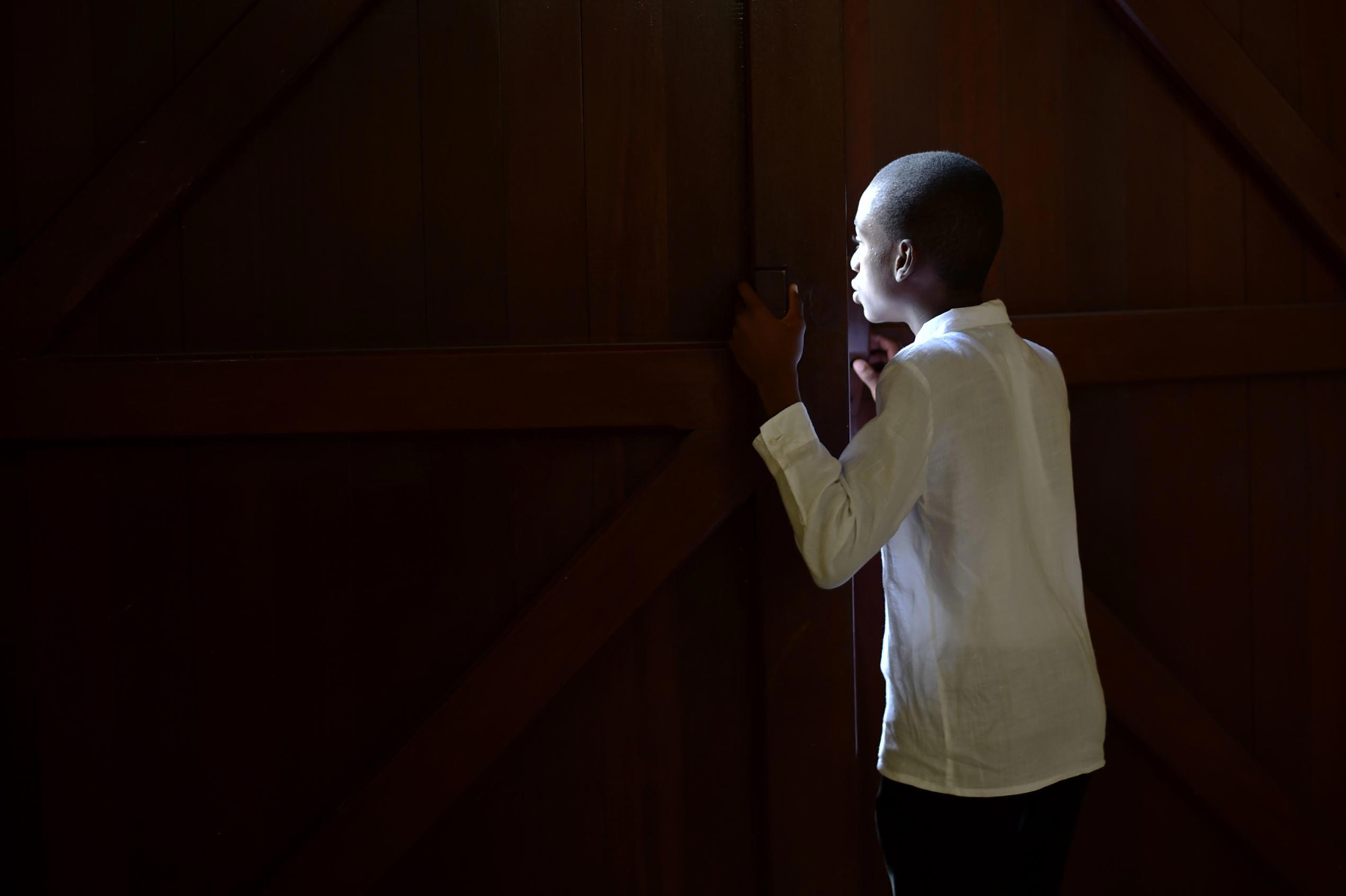 Slide 1 of 100: TOPSHOT - A boy looks between the doors of the St. Pierre Church, in the commune of Petion Ville, Port-au-Prince, on June 15, 2017, while waiting for the arrival of catholic faithful participating in a Precession of the Feast of God (Precession de la Fete Dieu, in French) to mark the celebration of Corpus Christi. The faithful walked in procession to St. Pierre Church, in Petion Ville, where a mass was held. / AFP PHOTO / HECTOR RETAMAL (Photo credit should read HECTOR RETAMAL/AFP/Getty Images)