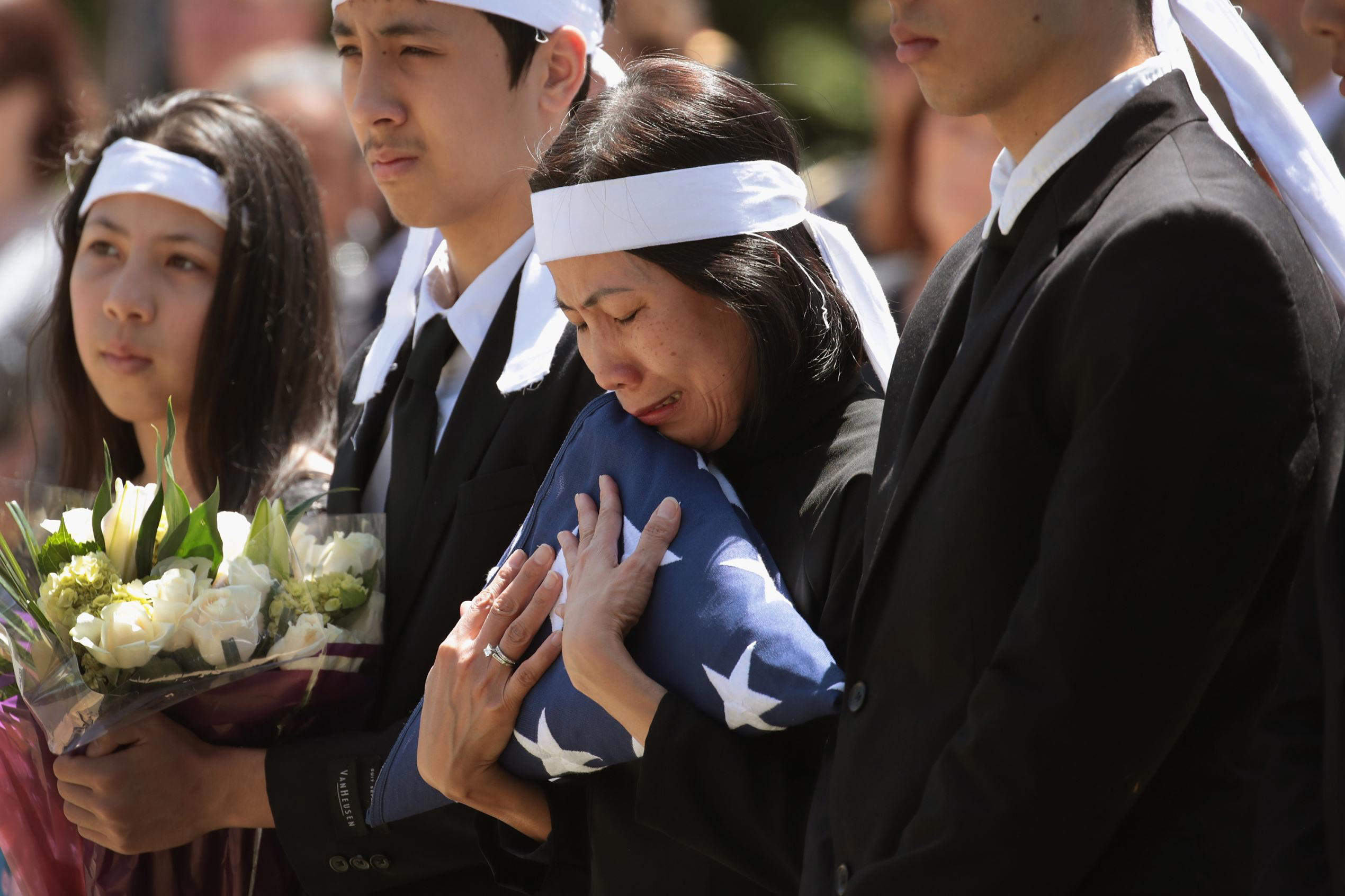 Slide 1 of 99: PORTLAND, OR - JUNE 05: Myhanh Best clutches the flag that draped the casket of her husband Ricky Best, an Army veteran and father of four, during a committal service at Willamette National Cemetery on June 5, 2017 in Portland, Oregon. Ricky Best, 53, and Taliesin Namkai-Meche, 23, were stabbed to death and Micah Fletcher,21, was severely injured after they tried to stop Jeremy Christian from harassing two teenage girls, one of whom was wearing a hijab, with racist taunts as they were riding a MAX commuter train. (Photo by Scott Olson/Getty Images)