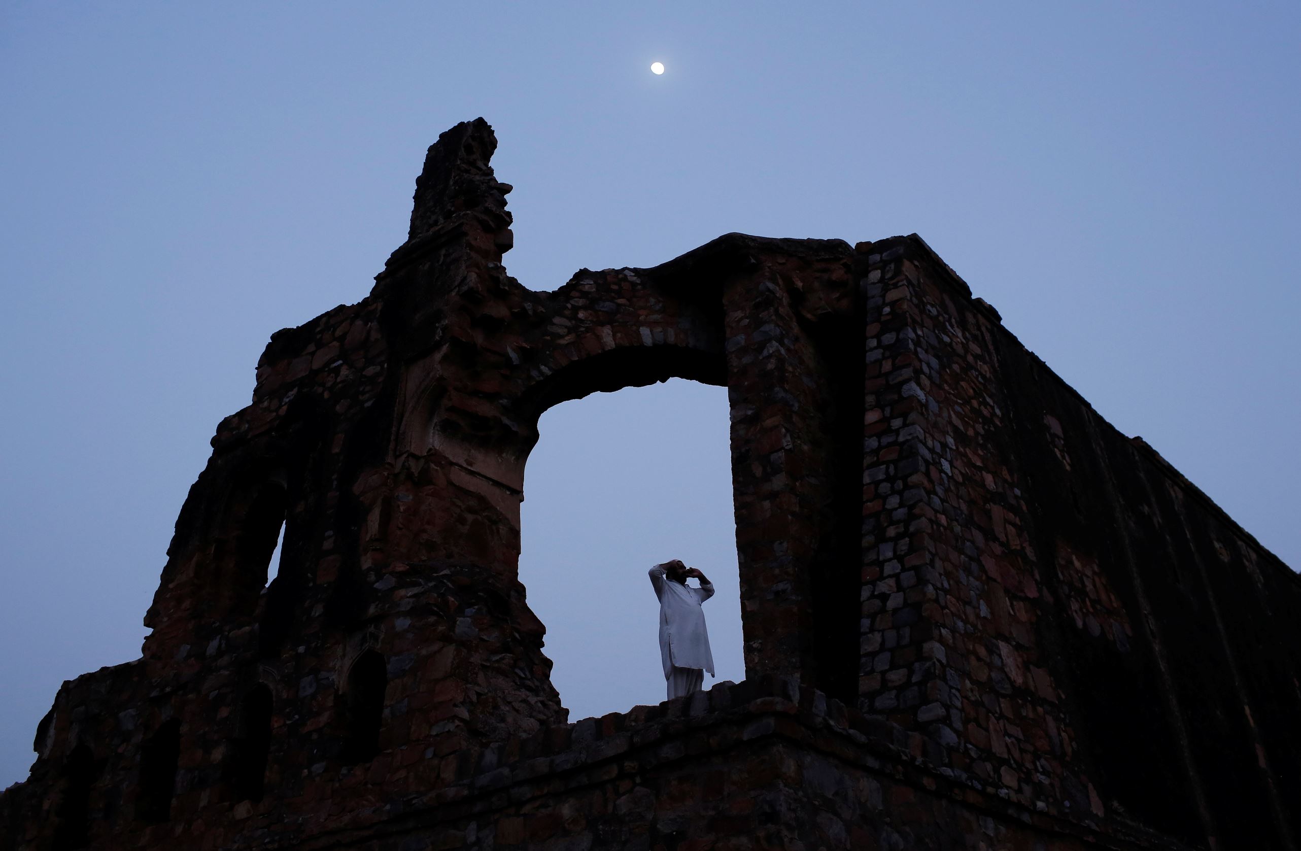 Slide 4 de 36: A Muslim man calls for the evening prayer after having his iftar (breaking of fast) meal during the holy month of Ramadan at the ruins of the Feroz Shah Kotla mosque in New Delhi, India, June 5, 2017. REUTERS/Adnan Abidi TPX IMAGES OF THE