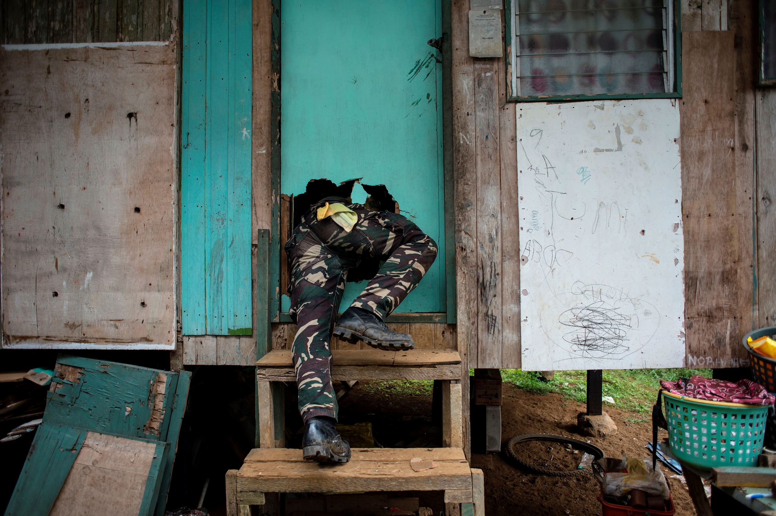 Slide 35 de 36: A soldier crawls through a hole through a door that he smashed during a house-to-house clearing operation against Islamist militants in Marawi, on the southern island of Mindanao on June 7, 2017. With bomb-proof tunnels, anti-tank weapons hidden in mosques, human shields and a 'mastery' of the terrain, Islamist militants holed up in a southern Philippine city are proving a far tougher opponent than military chiefs expected.