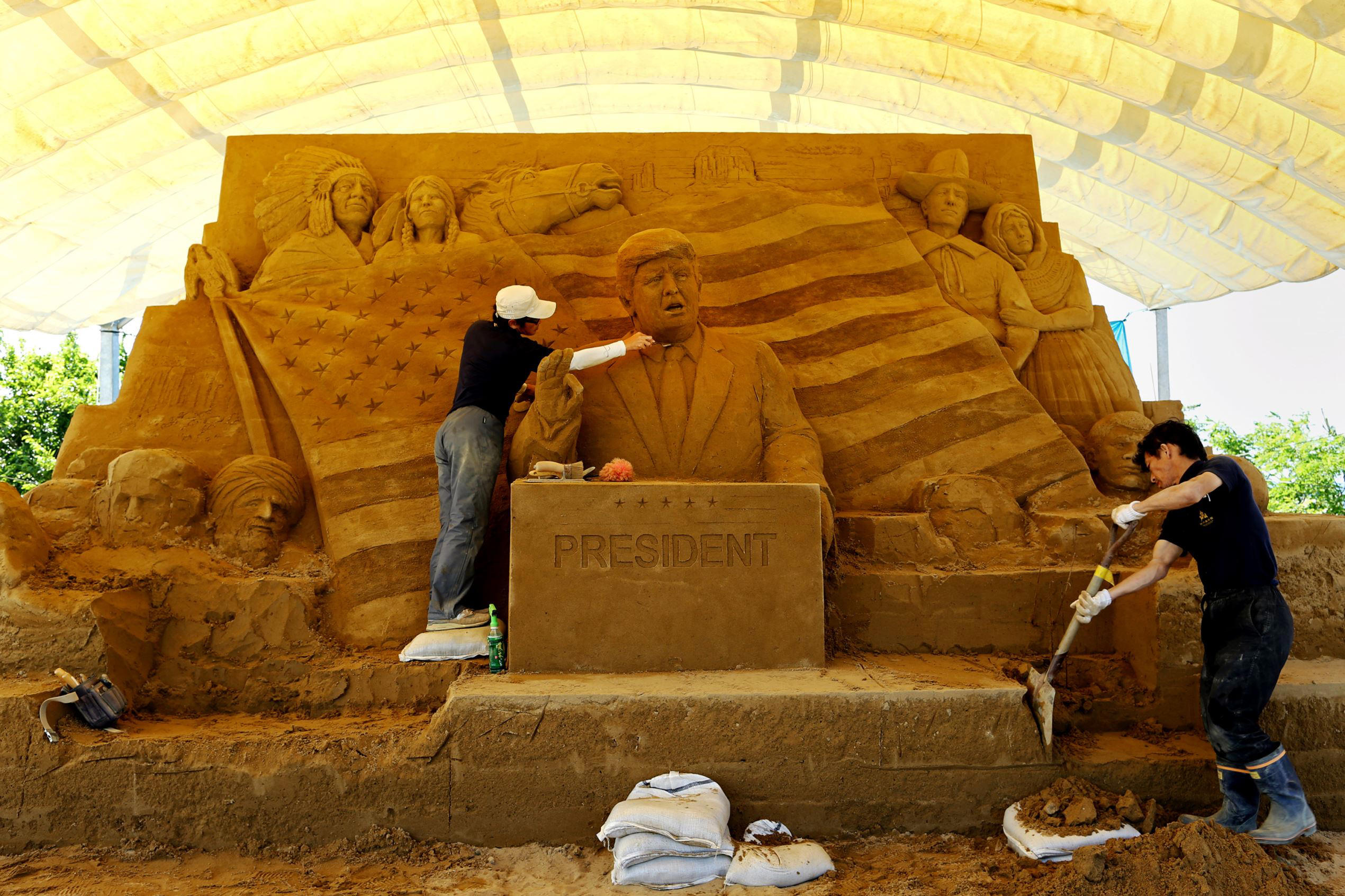 Slide 1 of 99: Katsuhiko Chaen(L), a sand sculptor and executive director of the Sand Museum works on a sculpture of US President Donald Trump during the 10th Annual Sand Sculpture Exhibition of 'Travel Around the World in Sand - The United States of America' at the Sand Museum in the Tottori Dune on June 11, 2017, in Tottori, Japan.  The exhibition will be on view until January 3, 2018.  (Photo by Buddhika Weerasinghe/Getty Images)