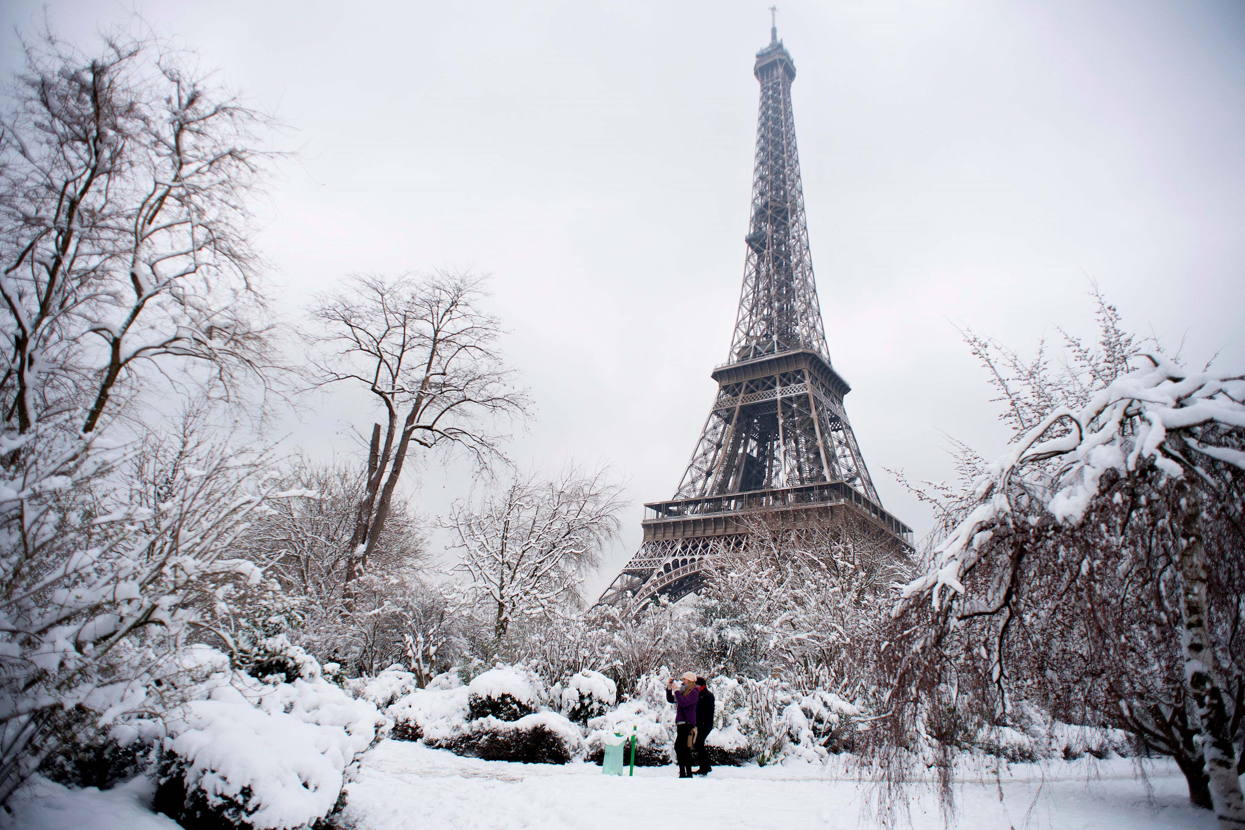 TOPSHOT - People walk through the snow covered Champ de Mars garden near the Eiffel tower on February 7, 2018 following heavy snowfall in Paris.
Exceptionally heavy snowfall brought public transport in Paris and surrounding regions to a near halt on February 7, spelling misery for commuters after hundreds were forced to abandon their cars to sleep in emergency shelters overnight.  / AFP PHOTO / ALAIN JOCARD        (Photo credit should read ALAIN JOCARD/AFP/Getty Images)