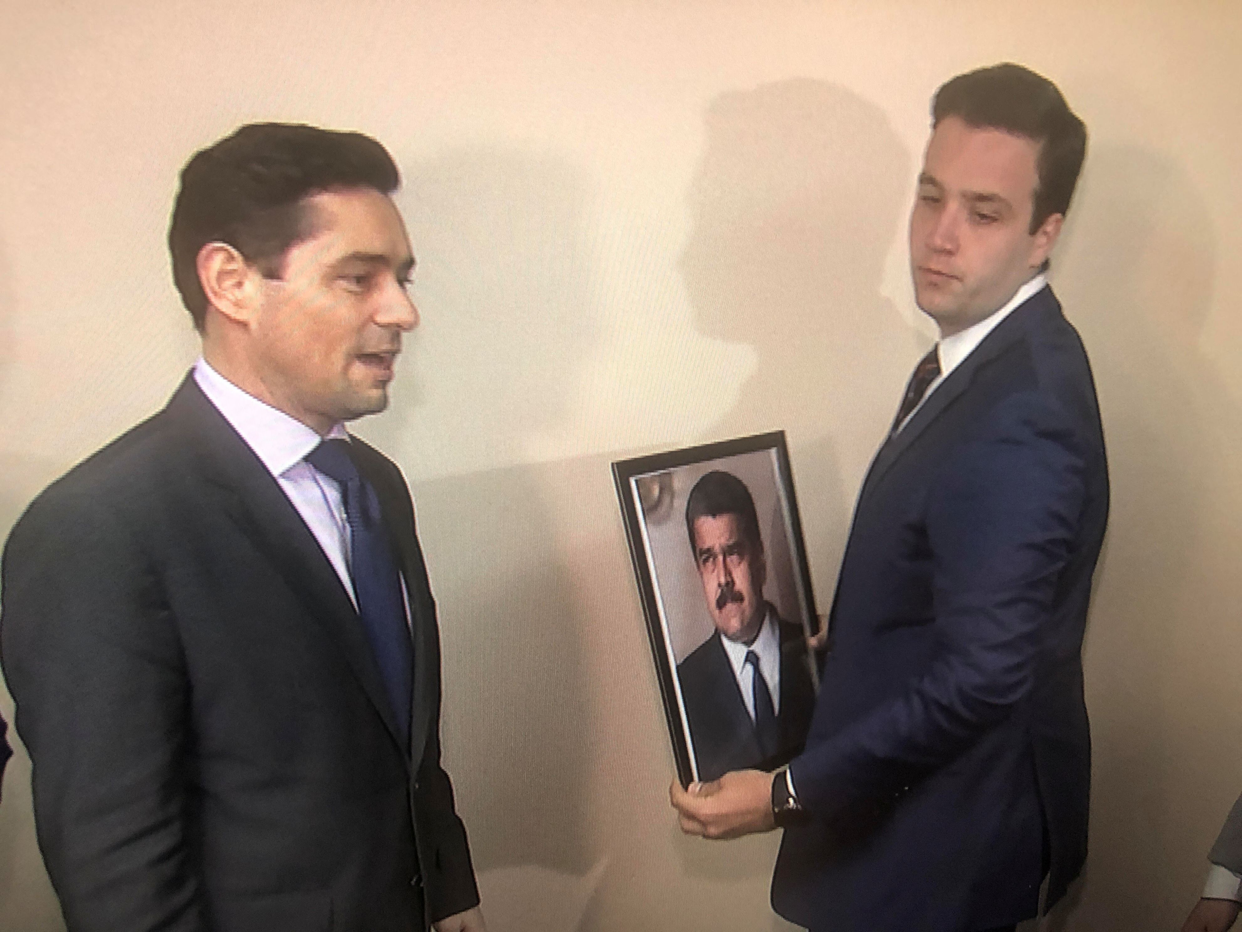 Carlos Vecchio (L), the envoy to the United States of Venezuelan opposition leader Juan Guaido, and an aide take down a picture of Venezuela's President Nicolas Maduro and replace it with a picture of Guaido in this frame grab from video after supporters of Guaido took control of the office of Venezuela's military attache in Washington, U.S. March 18, 2019.   REUTERS/Gershon Peaks