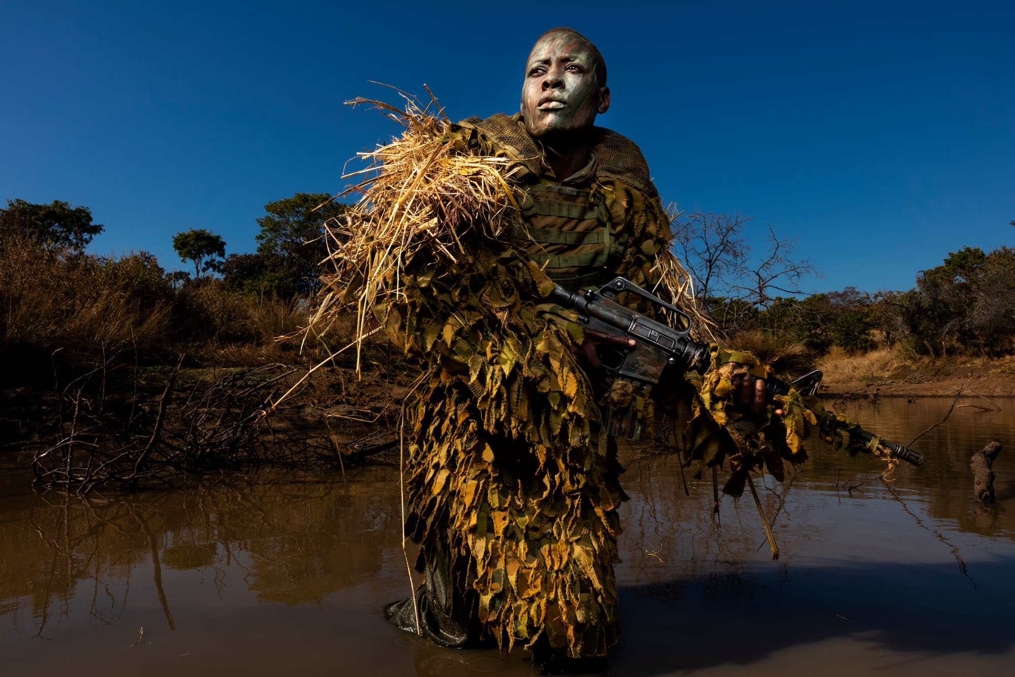 Phundundu Wildlife Area, Zimbabwe, June 2018. Petronella Chigumbura, 30, an elite member of the all-female Akashinga conservation ranger force undergoes stealth movement and concealment training in the bush near their base. Petronella says she previously worked on her ex-husband's family tobacco farm in slave-like conditions. This job has increased her self-respect and the salary enabled her to leave her abusive husband. She is now engaged in trying to get her children back and is being helped by the support of her ranger sisters to do so. Petronella is regarded by her instructors as easily as good as the best of the men they have trained for similar difficult conservation work. She also brings the added value of better community relations and intelligence gathering as a woman, the instructors are quick to add.