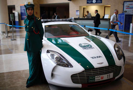 A police officer stands near an Aston Martin car used by Dubai police, during the Arabian Travel Market exhibition in Dubai May 6, 2013. REUTERS/Ahmed Jadallah (UNITED ARAB EMIRATES - Tags: CRIME LAW TRANSPORT TRAVEL BUSINESS)