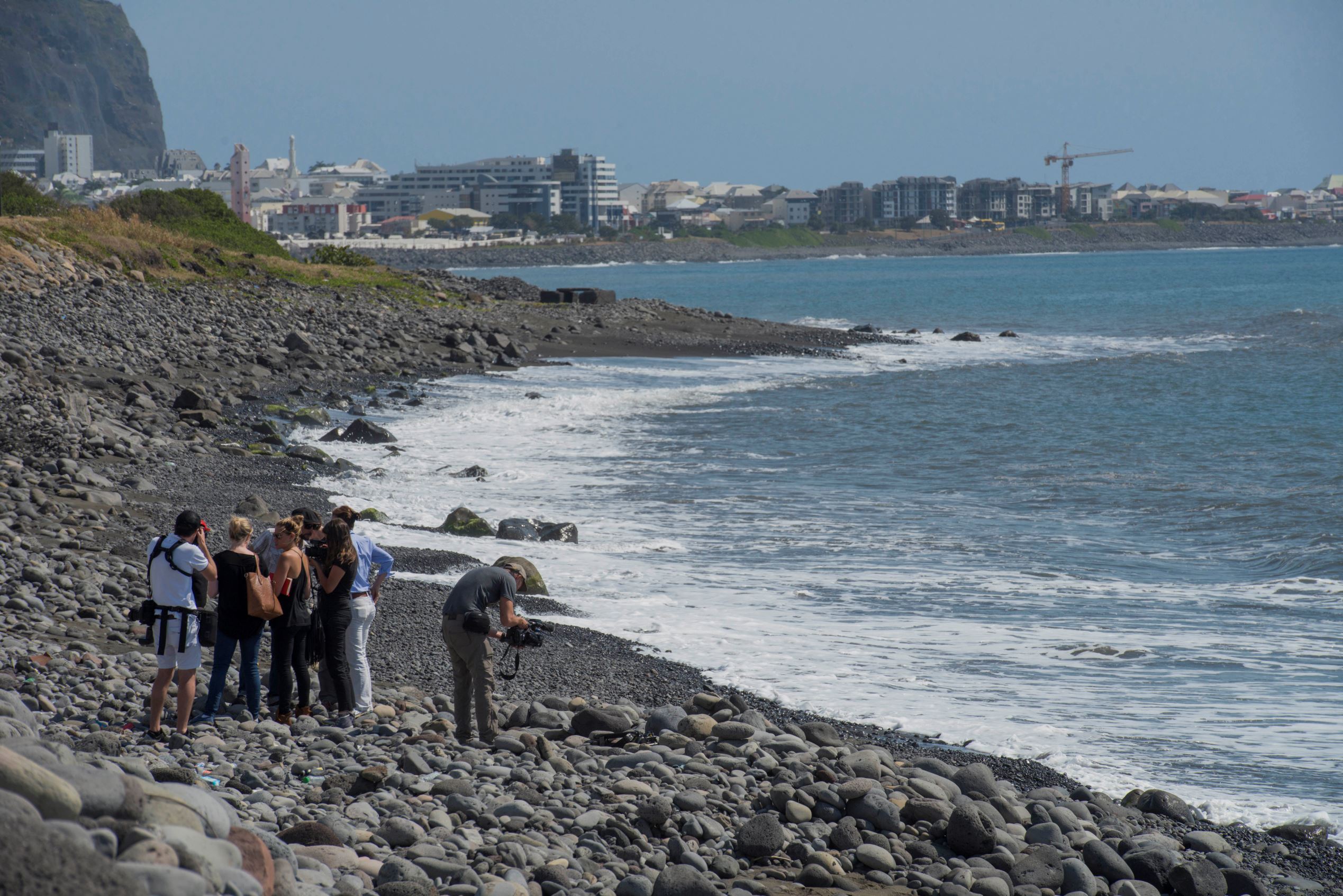 Workers search the beach for additional airplane debris where an airplane wing part was washed up on Reunion Island.