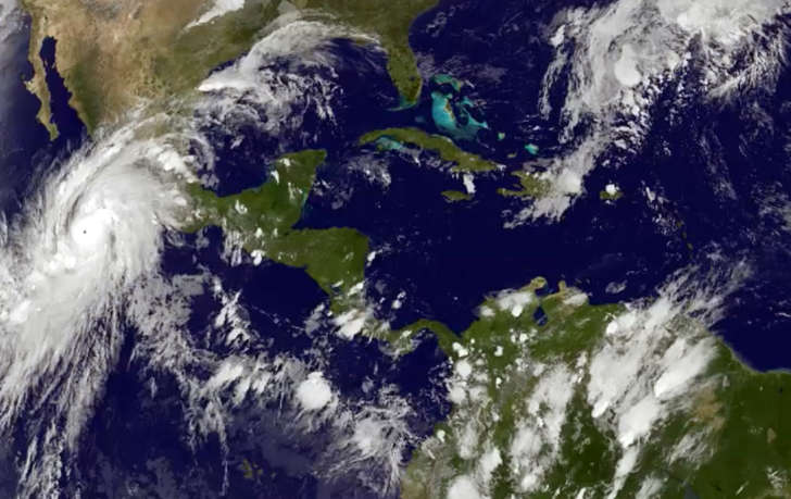 This satellite image taken at 8:45 p.m. EDT on Thursday, Oct. 22, 2015, and released by the National Oceanic and Atmospheric Administration shows Hurricane Patricia, left, moving over Mexico's central Pacific Coast.