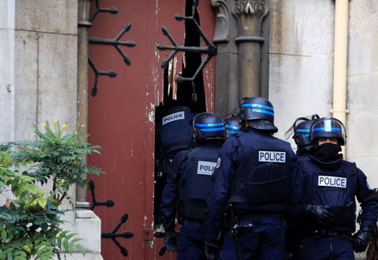 French police officers storm a church after a raid.