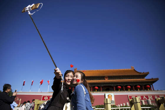 Girls take a selfie at the Tiananmen Gate as they celebrate National Day marking the 66th anniversary of the founding of the People's Republic of China in Beijing