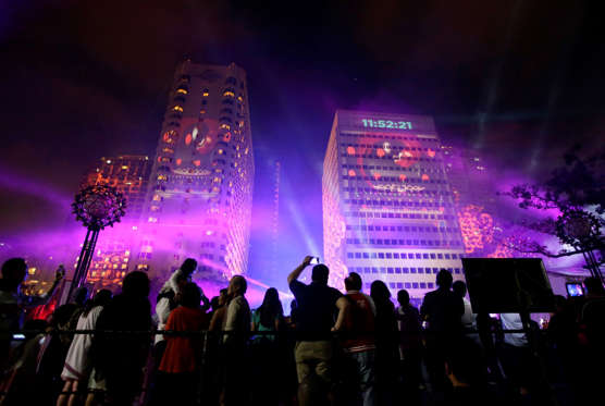 Revelers watch a laser show being projected on buildings as the countdown for the New Year begins in Manila, Philippines Wednesday, Dec 31 2014. Traditionally Filipinos welcome the New Year with firecrackers, fireworks and almost anything to make the loudest noise possible. (AP Photo/Bullit Marquez)