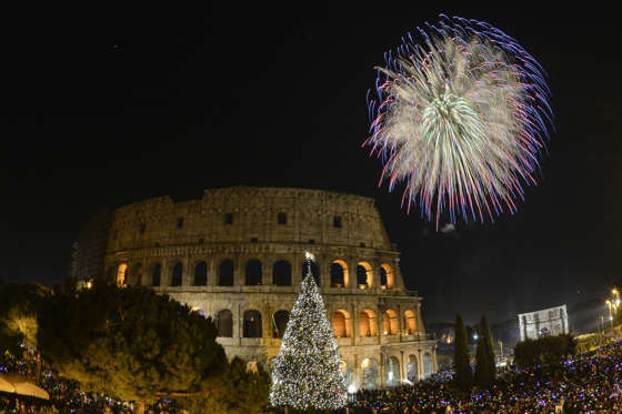 People cheer in front of Rome's ancient Colosseum as fireworks explode to celebrate the new year on January 1, 2015. AFP PHOTO / ANDREAS SOLARO (Photo credit should read ANDREAS SOLARO/AFP/Getty Images)