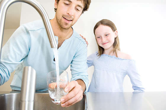 Man filling glass of water for daughter.