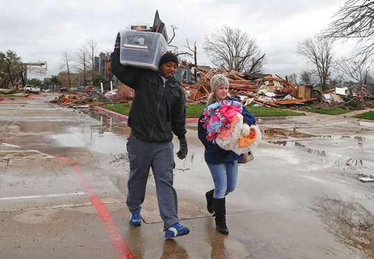 Ronnell Lincoln, 35, and Terri Fykora (L), 29, carry the belongings they were able to save from their residence at Landmark at Lake View North Apartments as the recovery process begins following tornadoes which hit the area late Saturday night December 28, 2015 in Garland, Texas. A meteorolocical assault of tornadoes, blizzards and heavy rain have left dozens dead and a large path of property damage in the Central, U.S.