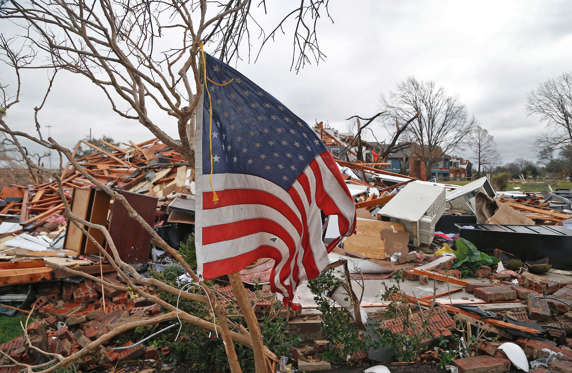 A tattered U.S. flag that had been attatched to a tree waves over the debris at the Landmark at Lake Village North Apartments as the recovery process begins following tornadoes which hit the area late Saturday night December 28, 2015 in Garland, Texas. A meteorolocical assault of tornadoes, blizzards and heavy rain have left dozens dead and a large path of property damage in the Central, U.S.