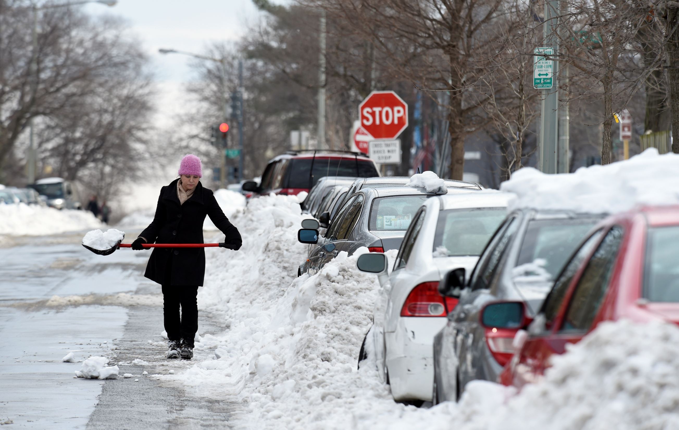 Grace McGuire of Washington shovels out her car in Washington, Tuesday, Jan. 26, 2016, as the nation's capital digs out following a monster weekend snow. East Coast cities hit hard by a massive snowstorm are getting closer to their normal routines after more than three days with life at a virtual standstill.
