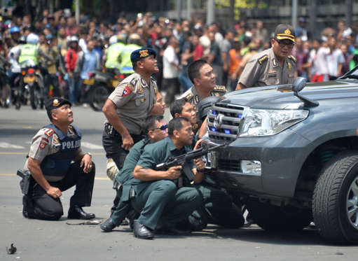Indonesian police take position behind a vehicle as they pursue suspects after a series of blasts hit the Indonesia capital Jakarta on January 14, 2016. A series of bombs killed at least three people in the Indonesian capital Jakarta on January 14, with shots fired outside a cafe as police moved in, an AFP journalist at the scene said.