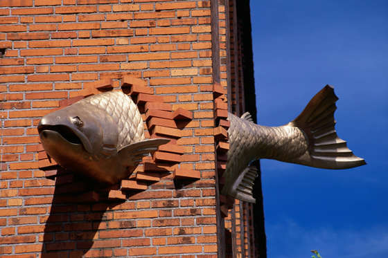 A sculpture of a fish that seems to swim through a brick wall graces the corner of the South Park Seafood Grill on Salmon Street.