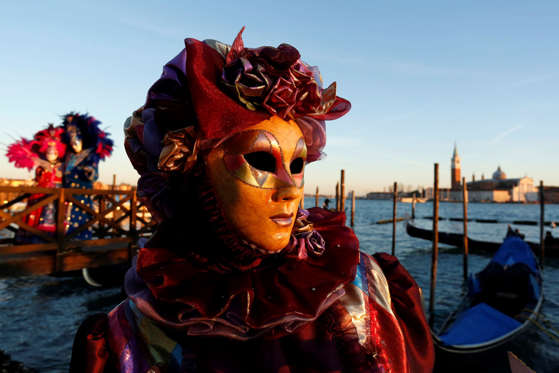 Costumed revellers pose for a photograph by the water at St Marks Square during the 2016 Carnevale di Venezia, in Venice, Italy, on Friday, Feb. 5, 2016. The annual Venice Carnival runs for ten days, ending on the Christian celebration of Lent.