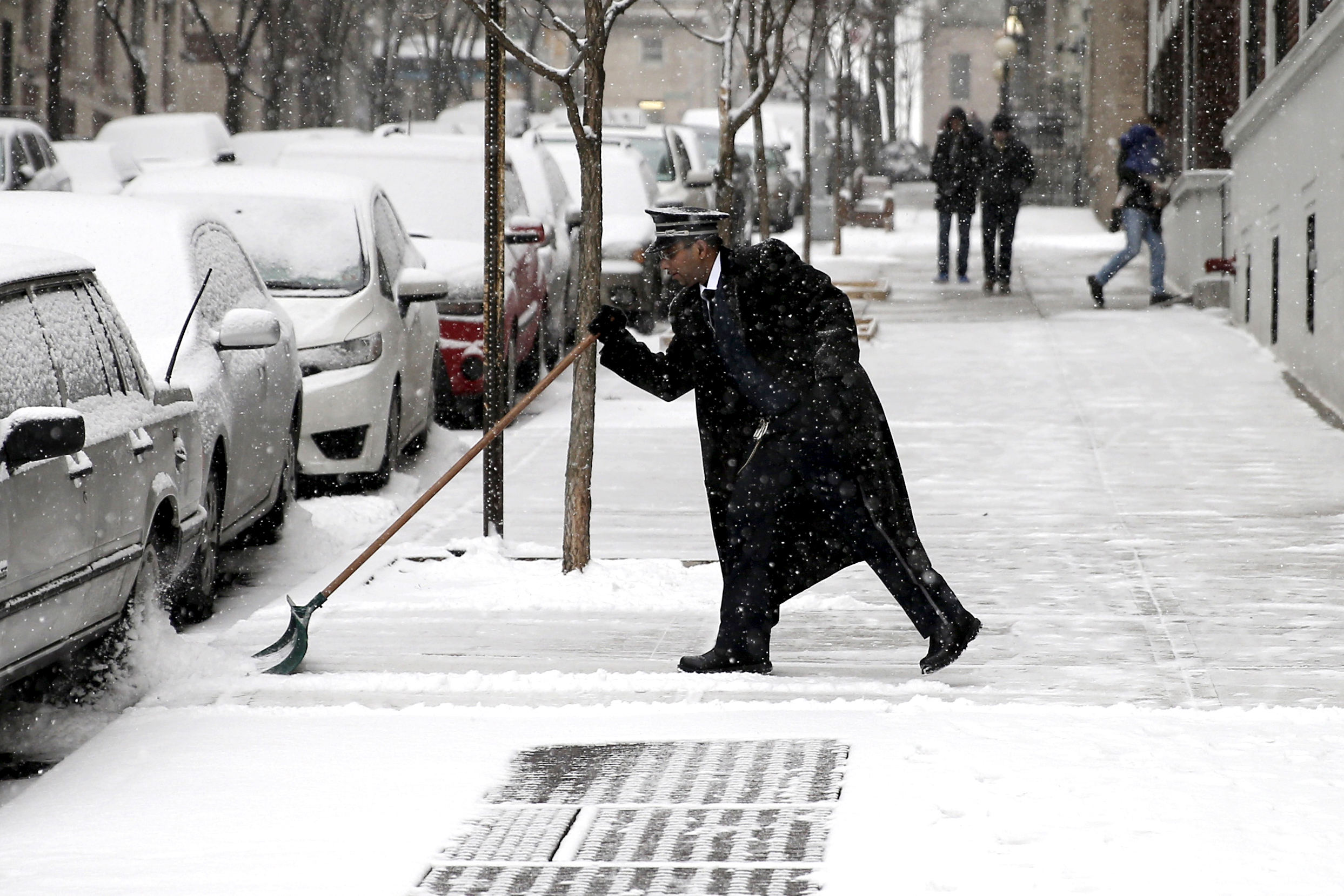 A doorman shovels snow near Riverside Drive on Feb. 15, 2016, in the Manhattan borough of New York City.