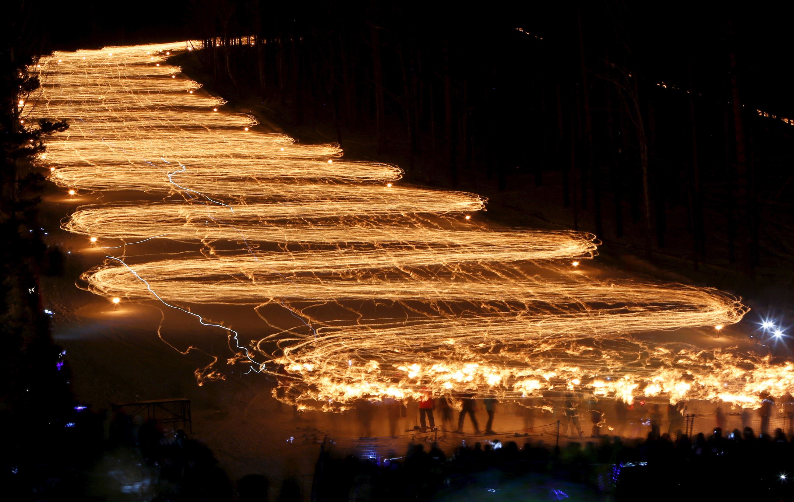 Spectators (bottom) watch hundreds of skiers descend from a slope while holding lit torches in the town of Zheleznogorsk, northeast of Krasnoyarsk, Siberia, Russia, February 27, 2016. Local residents organised the annual winter torch festival to promote sports and healthy lifestyle, according to the organisers. Picture taken with long exposure on February 27, 2016.