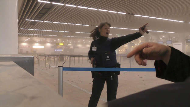 police officers directs passengers in a smoke filled terminal at Brussels Airport.