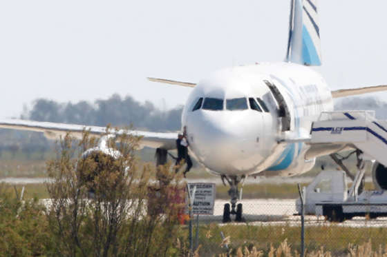 A man climbs out of the cockpit window an EgyptAir Airbus A-320 parked at the tarmac of Larnaca airport after being hijacked and diverted to Cyprus on March 29, 2016. The hijacker who seized the Egyptian airliner and forced it to land in Cyprus has been detained, Cypriot government spokesman Nicos Christodoulides said. / AFP / BEHROUZ MEHRI (Photo credit should read BEHROUZ MEHRI/AFP/Getty Images)
