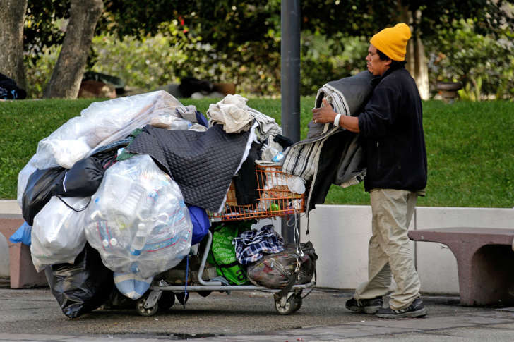 A homeless man packs up his blankets in downtown Los Angeles, Friday, Nov. 27, 2015.
