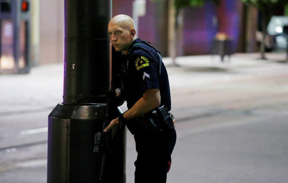 A Dallas policeman keeps watch on a street in downtown Dallas, Thursday, July 7, 2016, following reports that shots were fired during a protest over two recent fatal police shootings of black men.