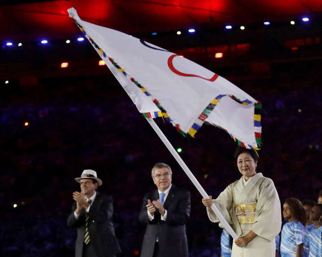 Tokyo Governor Yuriko Koike, right, waves the Olympic flag as Eduardo Paes, mayor of Rio de Janeiro, left, and IOC President Thomas Bach applaud during the closing ceremony in the Maracana stadium at the 2016 Summer Olympics in Rio de Janeiro, Brazil, Su
