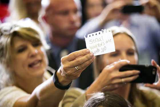 A member of the audience holds a piece of paper that reads "social workers are with yo" as Democratic presidential candidate Hillary Clinton greets supporters after giving a speech on the economy at Futuramic Tool & Engineering, in Warren, Mich., Thursday, Aug. 11, 2016.