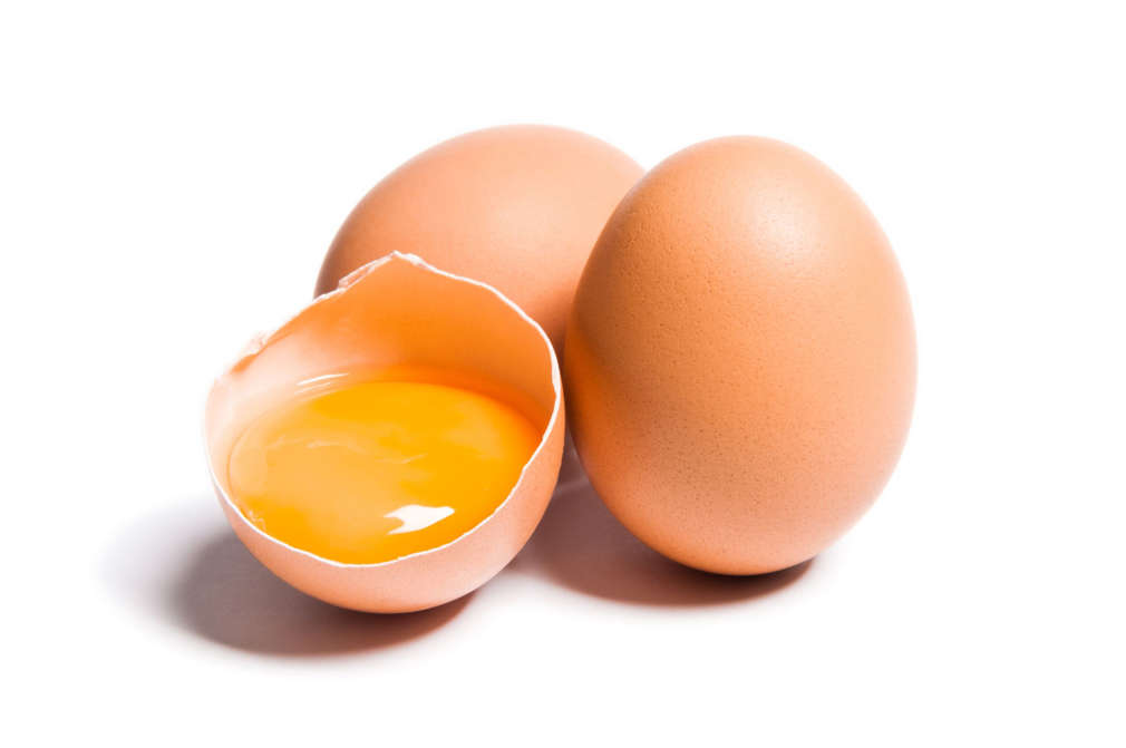 Group of brown raw chicken eggs, one is broken, yolk egg visible, isolated on white, studio shot.
Dominik Pabis