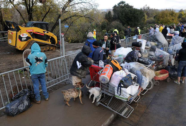 Displaced homeless people watch as a bulldozer removes their encampment known as The Jungle on Dec. 4, 2014, in San Jose, Calif.