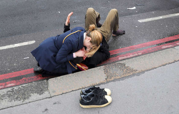 Slide 32 of 34: A woman assist an injured person after an incident on Westminster Bridge in London, March 22, 2017.