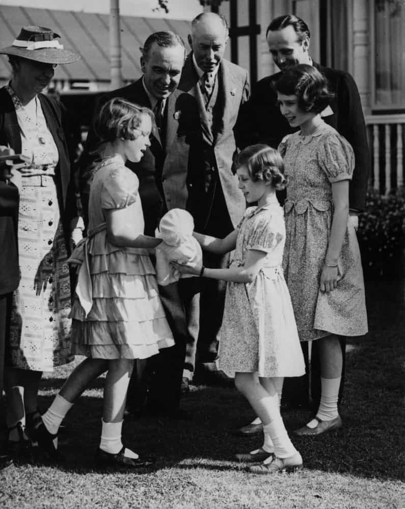 <p>In this February 7, 1932 photograph, Princess Elizabeth (right) watches Princess Margaret receive a presentation doll on behalf of elementary school girls during a ceremony in Windsor Great Park.</p>