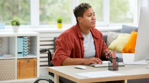 A person in a wheelchair working at a laptop.
