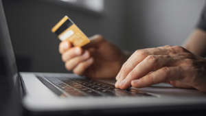 Shopping online. Young man using laptop with credit card at home