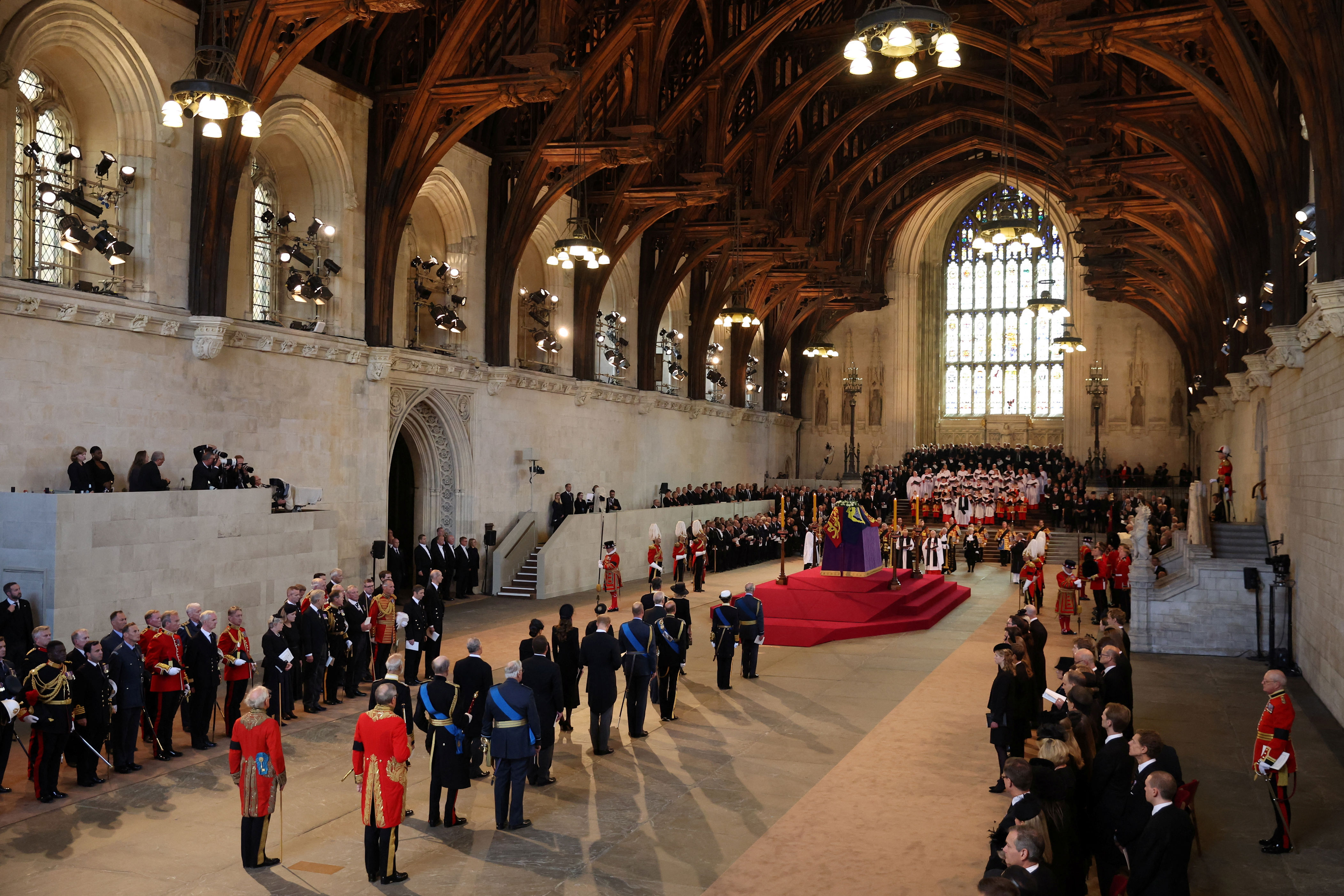 <p>The royal family stands behind the coffin of Queen Elizabeth II, adorned with a royal standard and the Imperial State Crown, after her body arrived at Westminster Hall from Buckingham Palace in London for her lying-in-state on Sept. 14, 2022. </p>