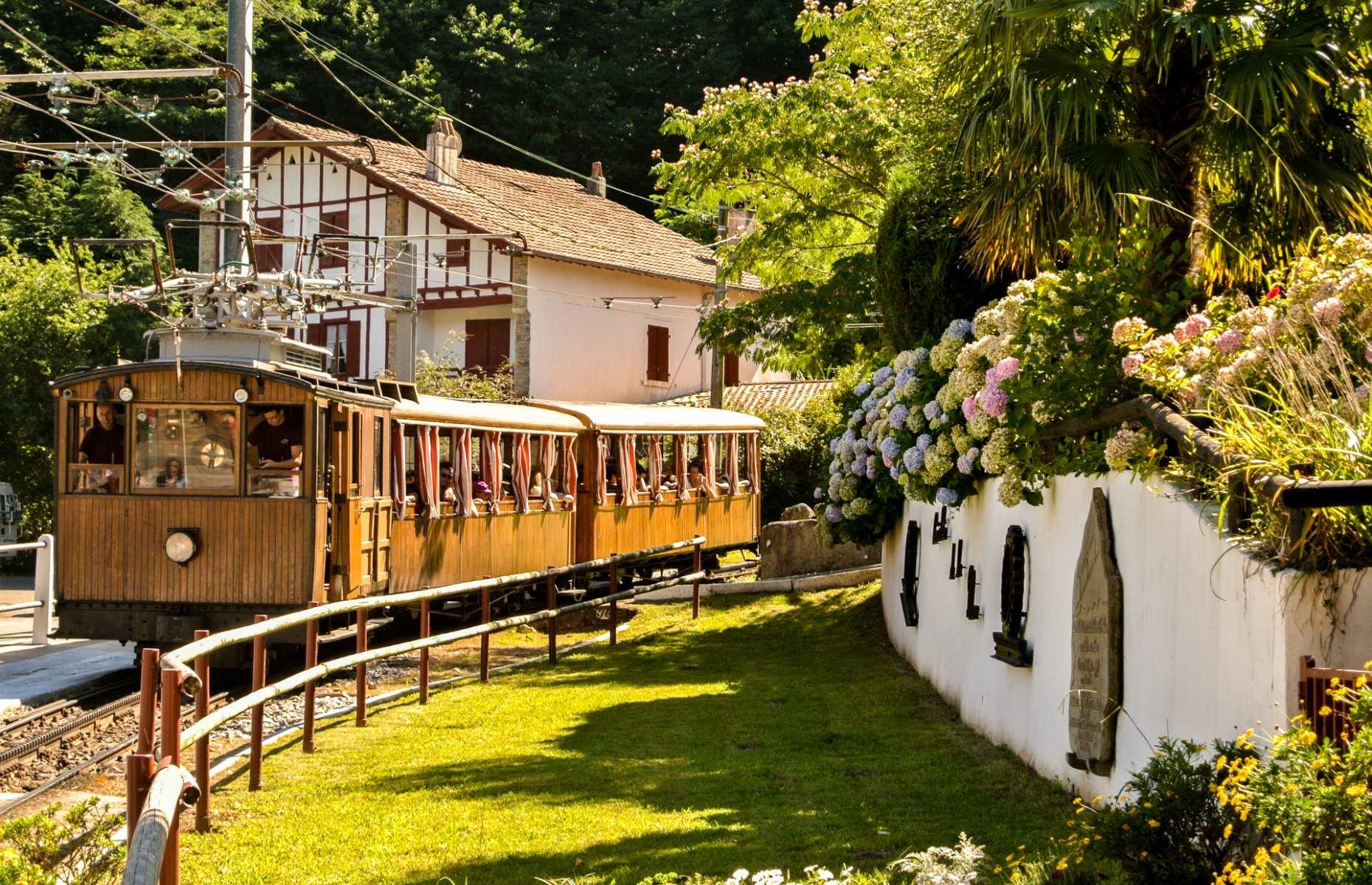 <p>You’d be hard-pressed to find a much more adorable train journey than this. Located in France’s captivating Basque Country, the <a href="https://www.rhune.com/en/">Rhune Railway</a> (or Le Petit Train de la Rhune) is a fabulous cog railway which takes passengers on a 35-minute ascent up to the 2,969-foot (905m) summit of its namesake mountain. The picture-perfect chestnut-wood carriages have been navigating this steep section of track since 1924.</p>