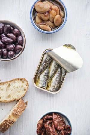 Tin can of sardines in oil, bowls of pickled vegetables and slices of bread
