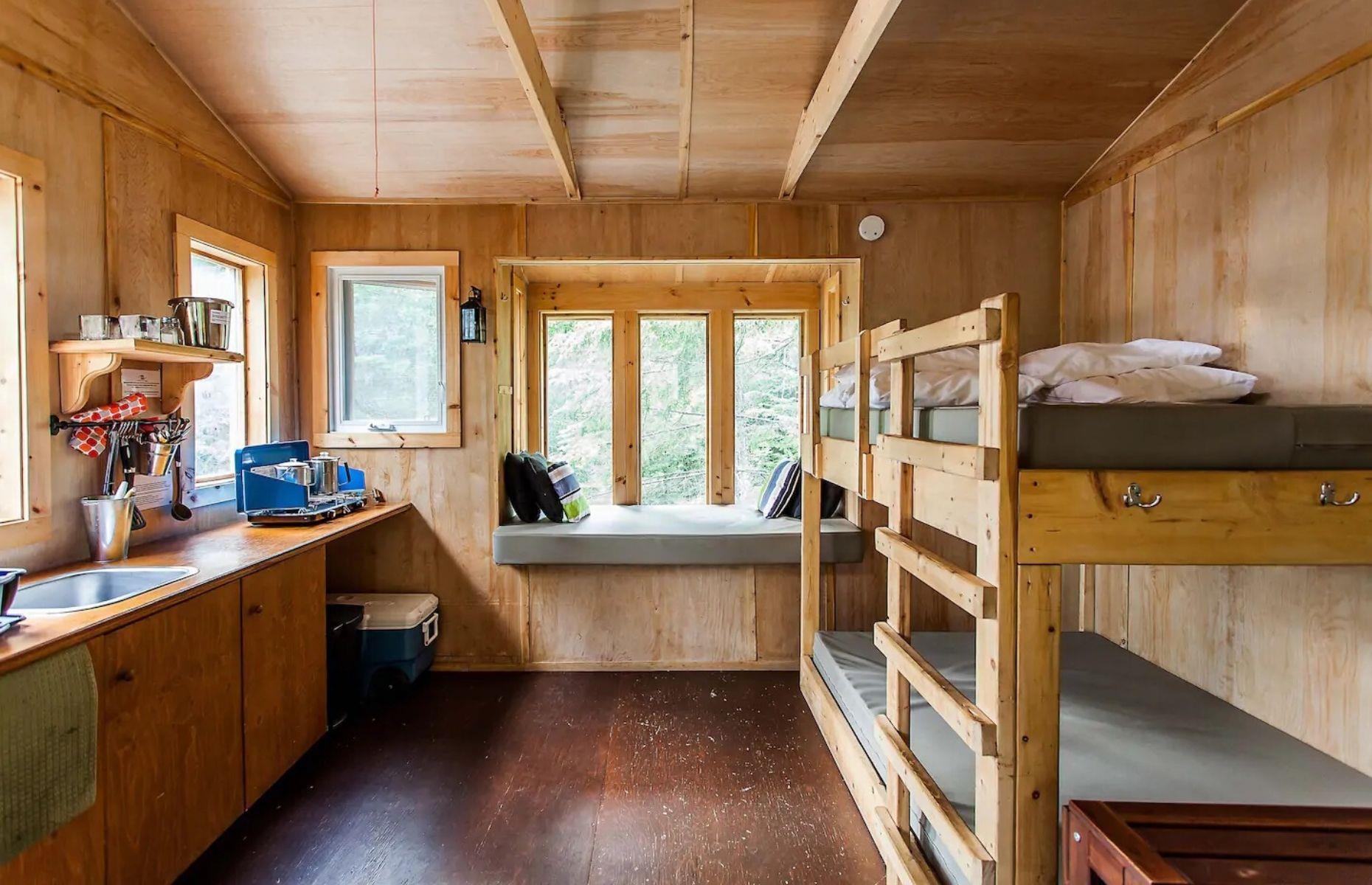 <p>Suitable for up to six people at any one time, this cozy cabin offers just one small room, yet it features everything a person could possibly need. There's a basic kitchen, comfy bunk beds, and a small seating area and wood-burning stove for post-hike R&R! Plus, thanks to its natural timber palette and minimalist fixtures, this rustic treehouse offers a real taste of off-grid living.</p>