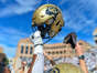 BOULDER, CO - OCTOBER 15: A Colorado Buffaloes helmet is held in the air as Colorado Buffaloes players celebrate on the field after an overtime win against the California Golden Bears at Folsom Field on October 15, 2022 in Boulder, Colorado. (Photo by Dustin Bradford/Getty Images)
