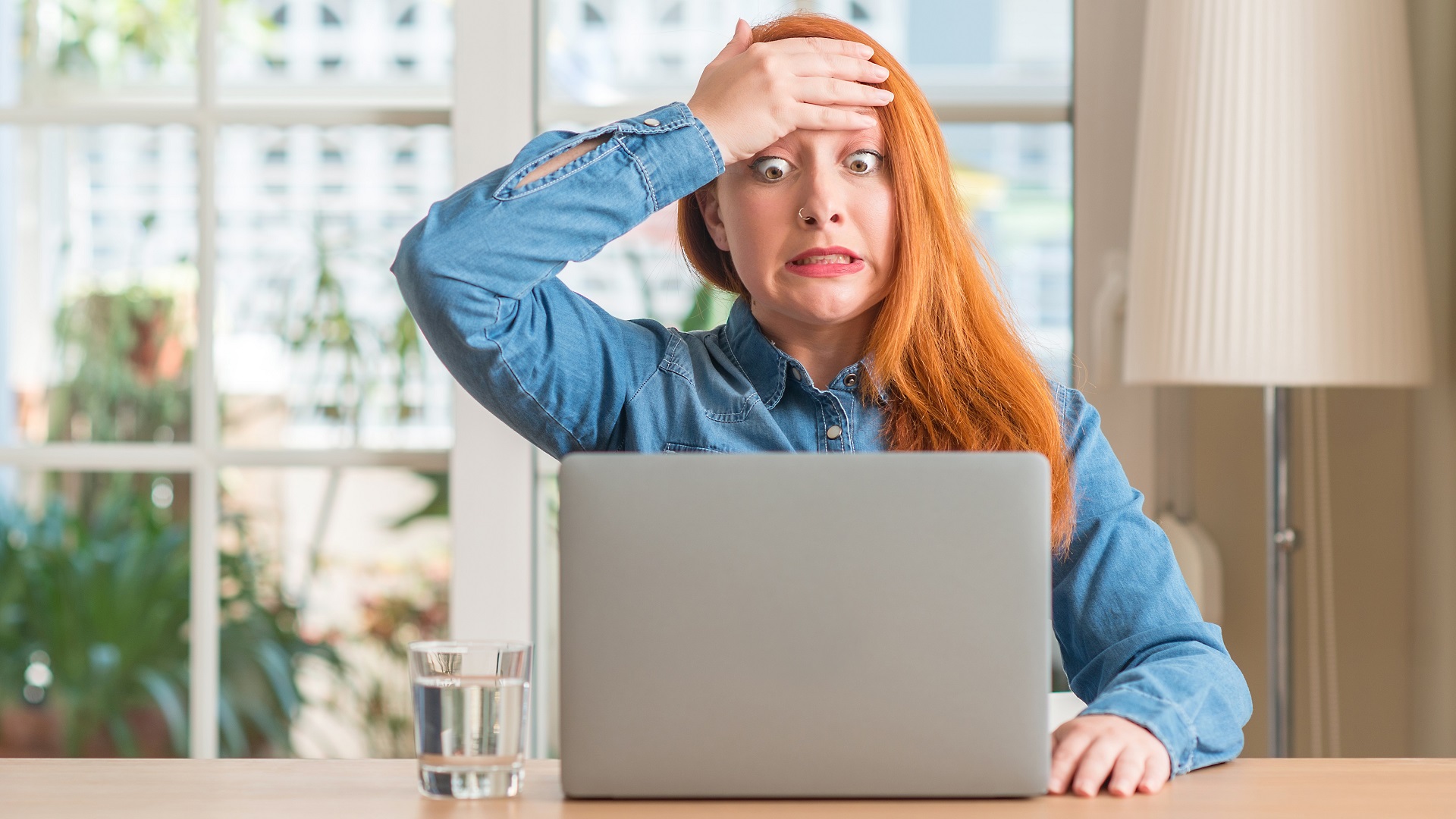 stresses surprised woman laptop hands on head_iStock-1041334030