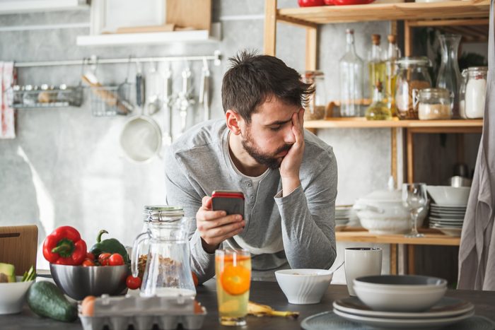 Sad man using smart phone during breakfast at home