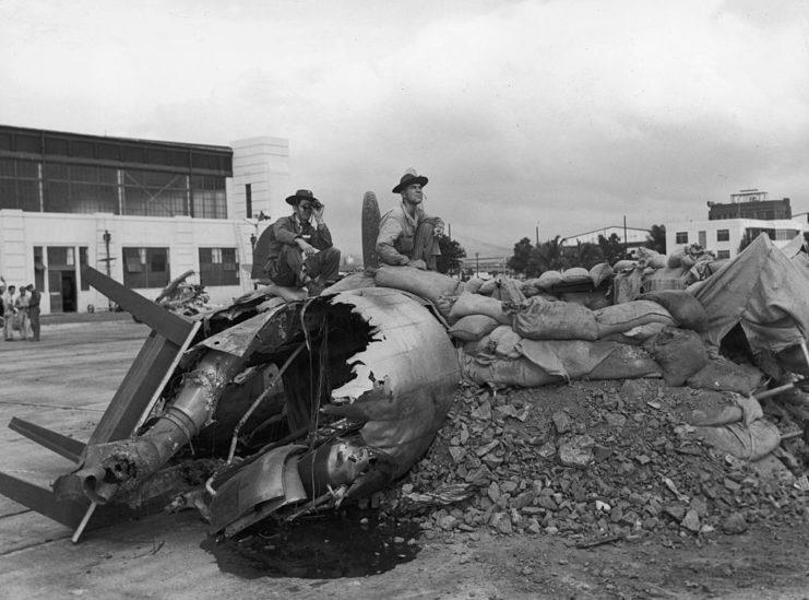 <p>US military personnel sitting on the remains of one of the many aircraft that were destroyed during the attack on Pearl Harbor. Hickam Field was one of the first targets of the bombardment, to prevent a counterattack from the air.</p>