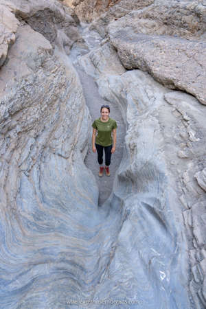 Woman hiking a narrow trail wit soft stone from erosion smooth surfaces