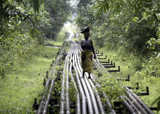 File photo: A woman walks along an oil pipeline in Warri, Nigeria.